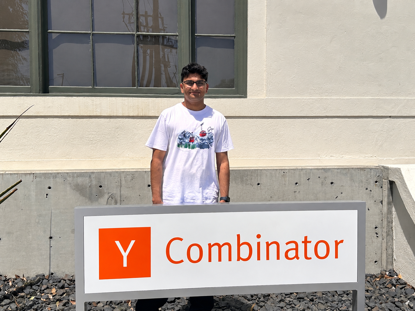 Vedant Soni standing behind the Y Combinator sign